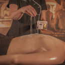 Een masseur strooit ceylon sea salt scrub over haar gast heen tijdens een ceylon behandeling 